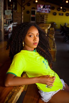 A young woman in casual attire enjoys a drink at a rustic indoor bar.