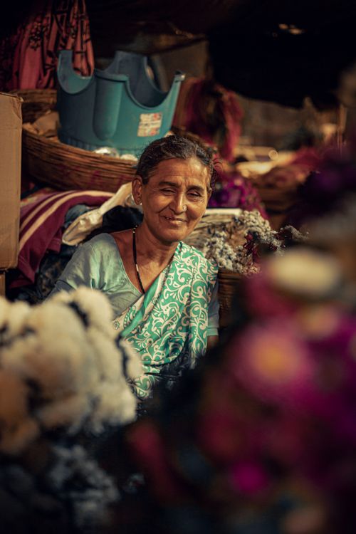 Free Portrait of a smiling woman selling flowers at a vibrant market in Mumbai, India. Stock Photo