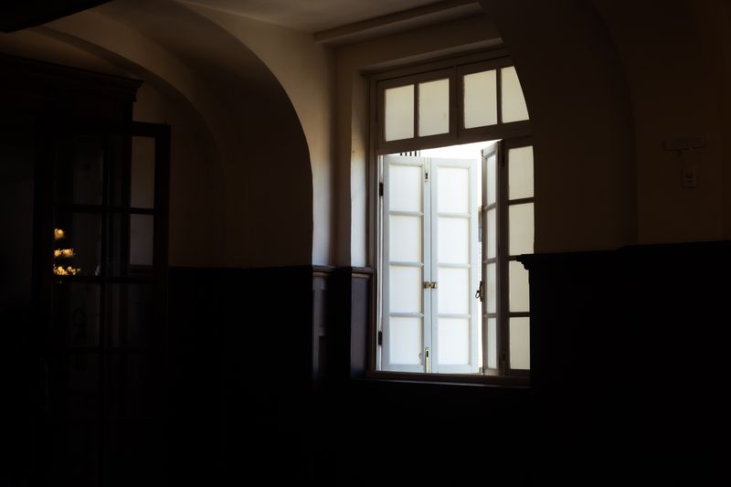 Interior of a dark room featuring an open window with white frame and glass panels.