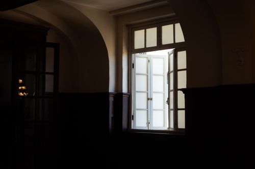 Free Interior of a dark room featuring an open window with white frame and glass panels. Stock Photo