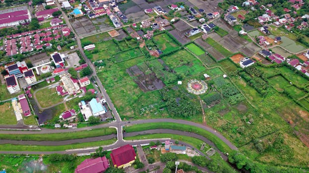 Drone shot of lush green farmlands and buildings in Baiturrahman, Aceh, Indonesia.