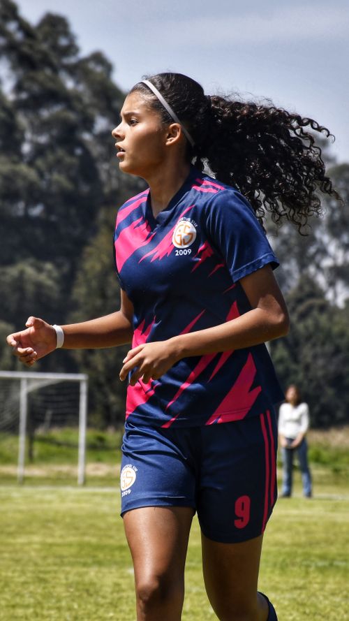 Free Woman playing football outdoors in bright sports clothing during the day. Stock Photo