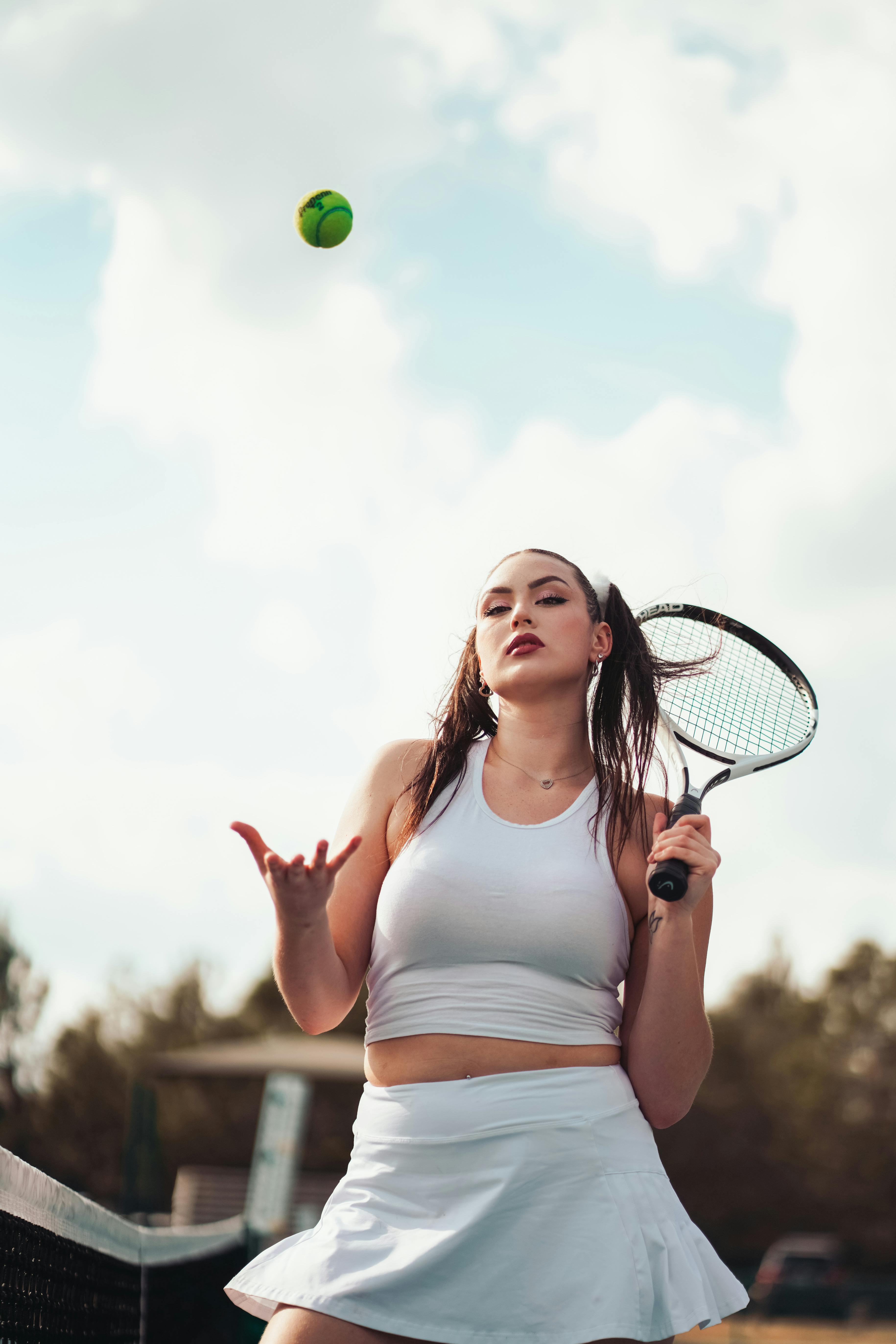 woman with tennis racket tossing tennis ball