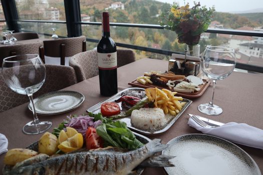 Elegantly set table with wine and gourmet dishes, offering a picturesque view of the landscape. - Fotografer Sidoarjo