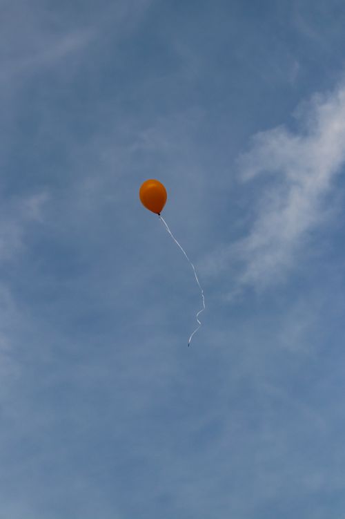 Free An orange balloon drifting against a serene blue sky, symbolizing freedom and flight. Stock Photo