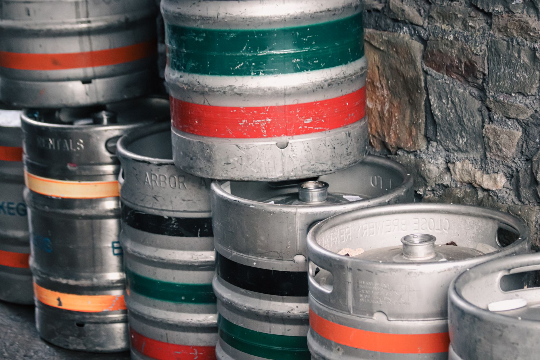 Friends clinking beer glasses around a keg setup outdoors on a sunny day