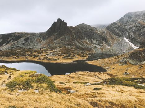 保加利亚有一个山间湖泊，被岩石地形和薄雾笼罩的山峰环绕