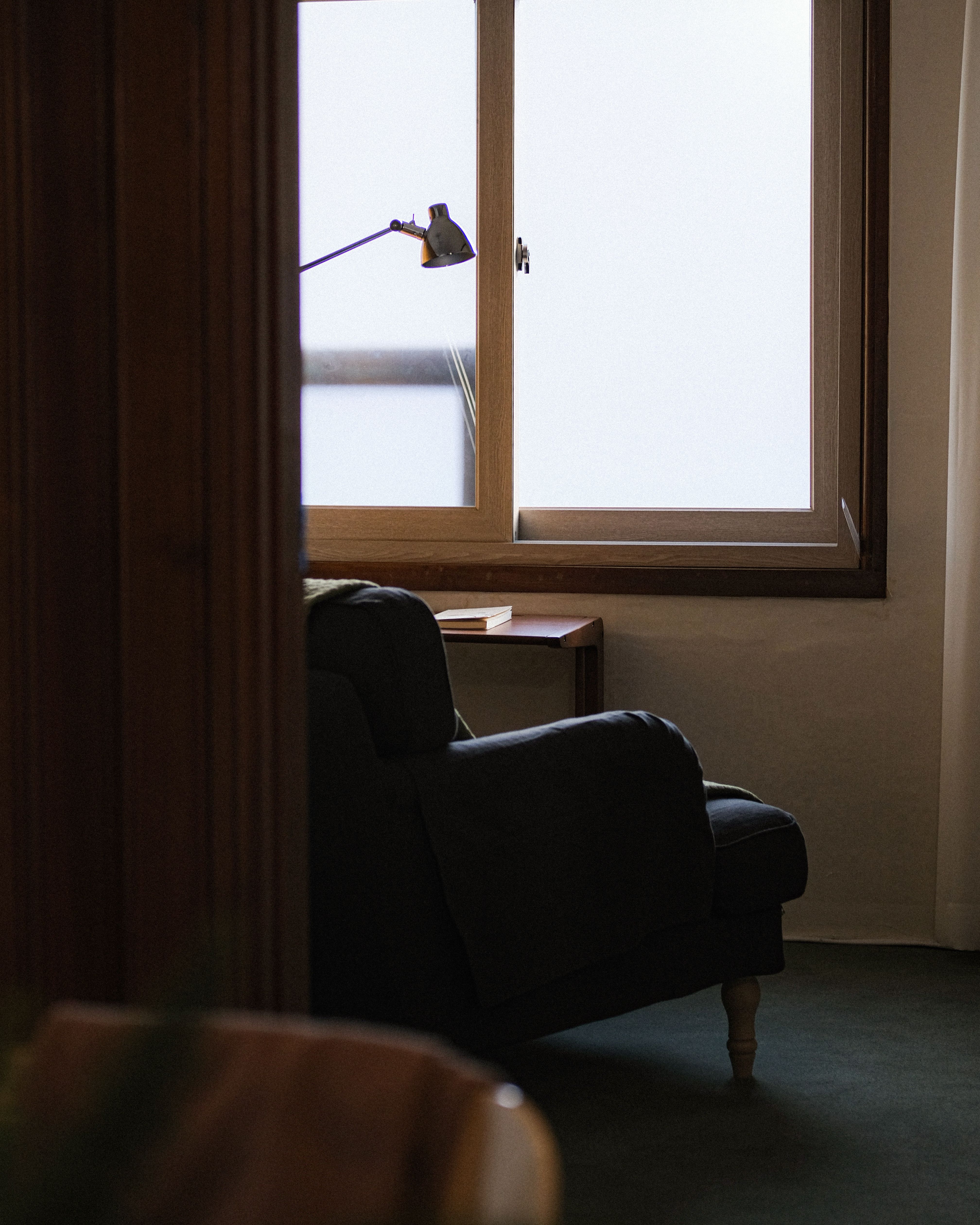 A comfortable armchair by a window in a peaceful, warm-lit interior
