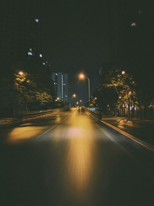 Free A dimly lit city street at night, showcasing urban solitude and atmospheric lighting. Stock Photo