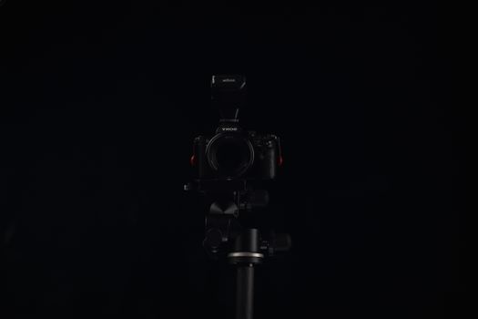 A professional camera setup on a tripod with a dark background, ideal for studio photography concepts.
