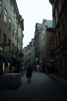 Explore a historic European street scene with classic architecture and pedestrians at dusk.