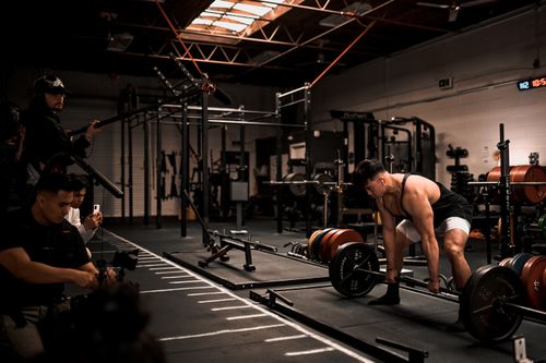 Free Muscular man performs deadlift in a gym with film crew documenting, showcasing strength and focus. Stock Photo