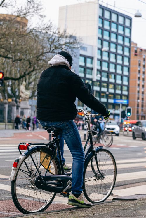 Free A man in a jacket cycles through city streets on a cold day. Stock Photo