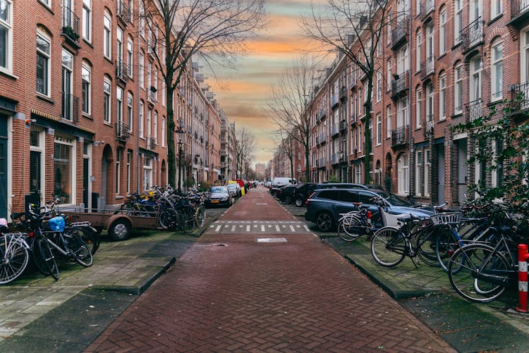 Vehicles And Bicycles Parked Near Brick Buildings