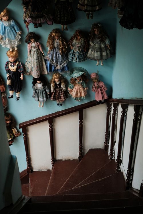 Free A collection of vintage dolls displayed on a wall by a stairwell inside a home. Stock Photo