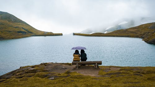 Women Sitting under Umbrella by Lake