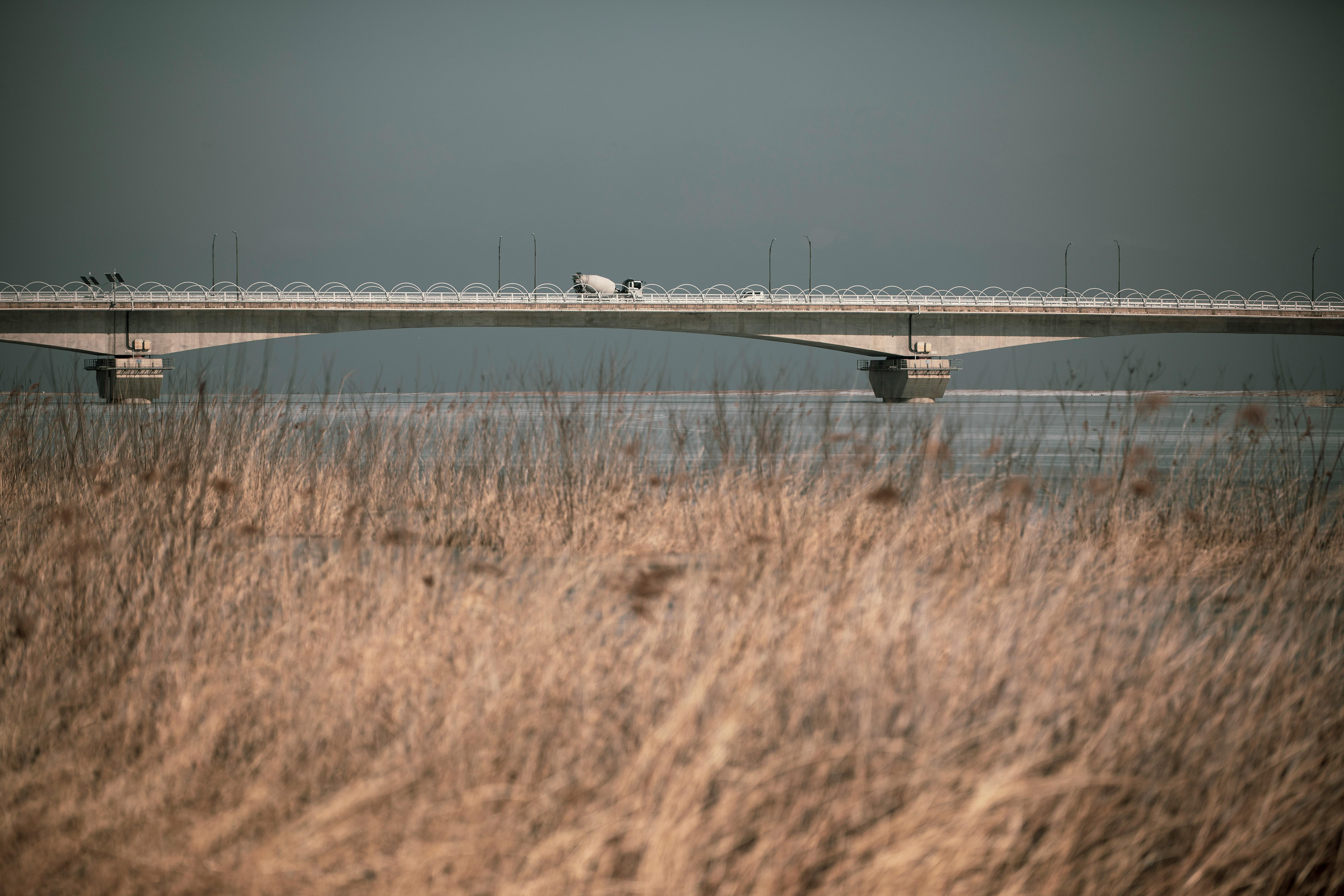 Free Bridge over a river in Yangyang, South Korea, with dry grass in the foreground and a clear sky in the background. Stock Photo
