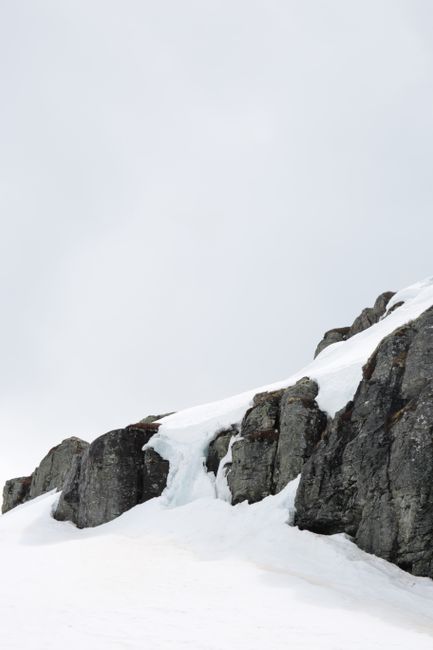 Capture of a cold, eroded rocky terrain lightly dusted with snow under an overcast winter sky.