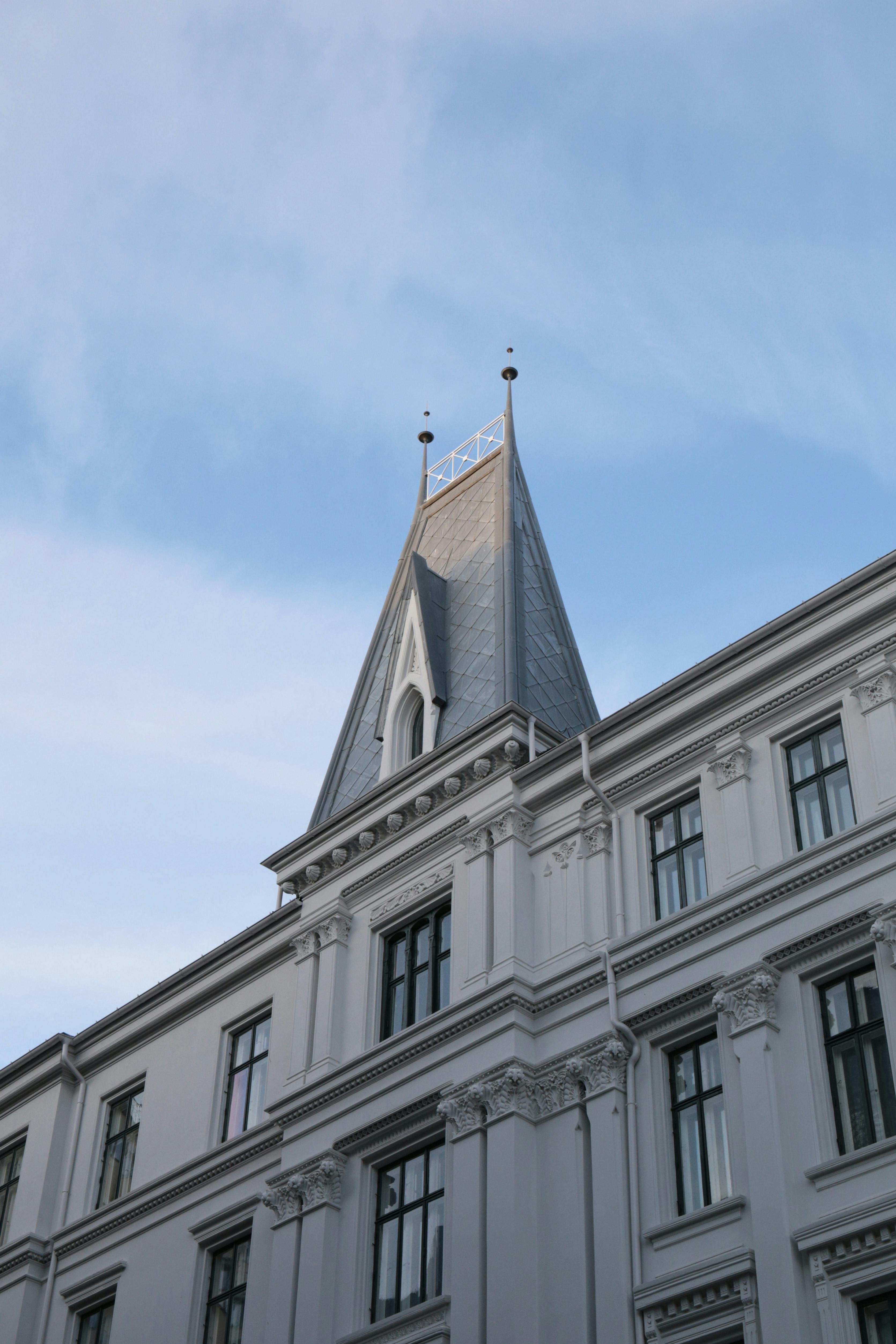 A beautifully detailed white facade with a pointed roof under a clear blue sky, showcasing architectural elegance.