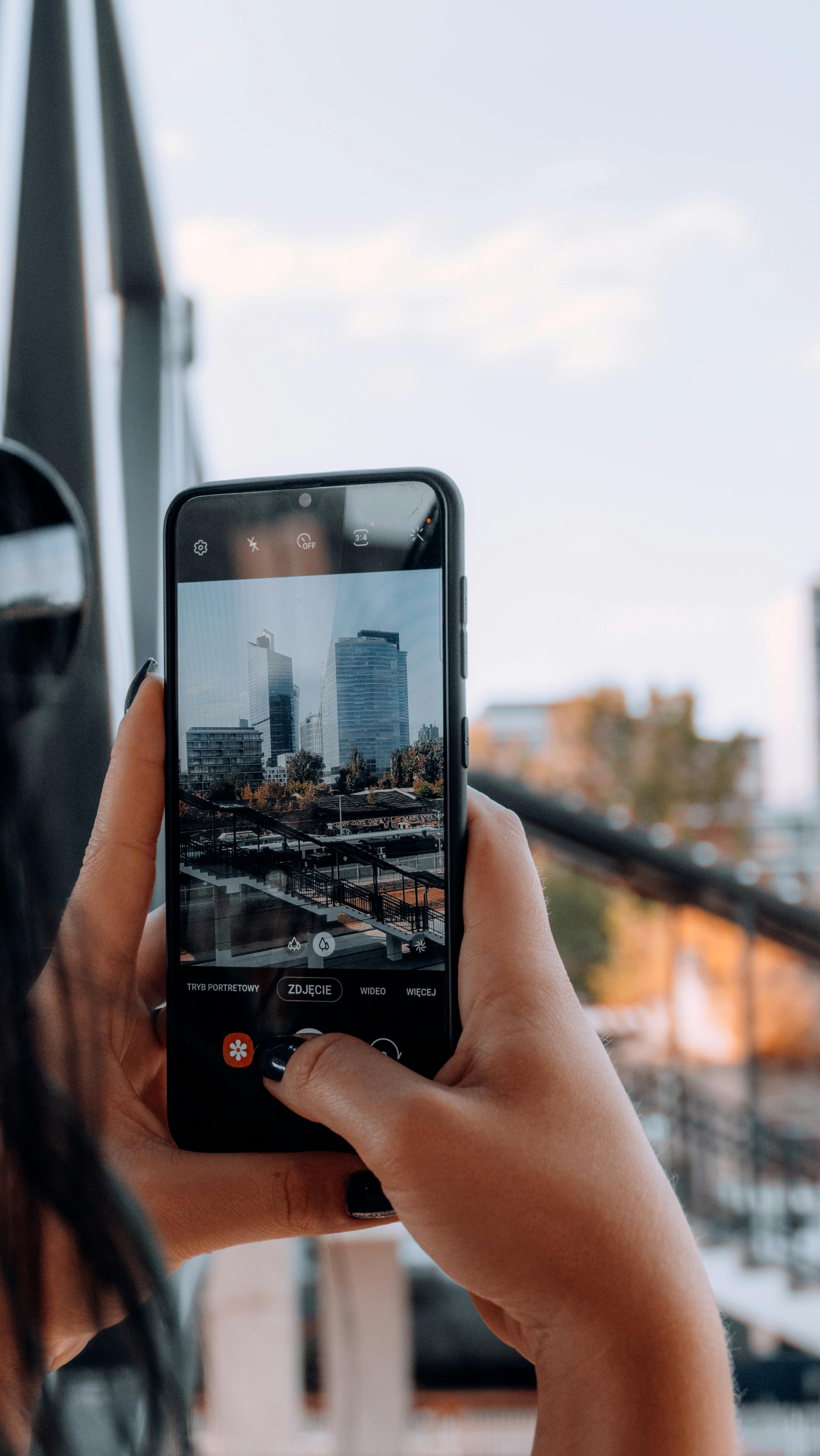 Close-up view of person photographing cityscape with a smartphone.