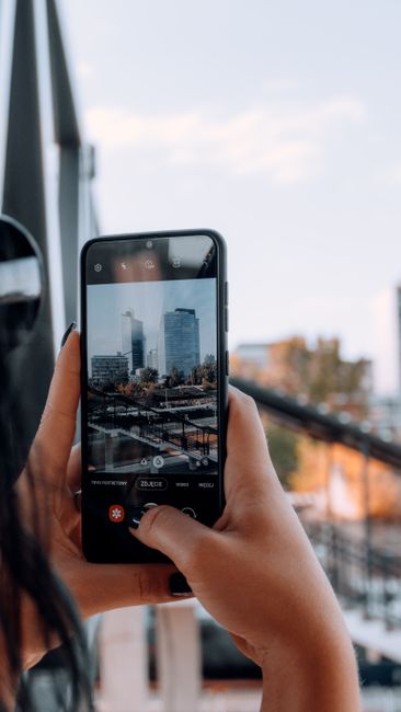 Close-up view of person photographing cityscape with a smartphone.