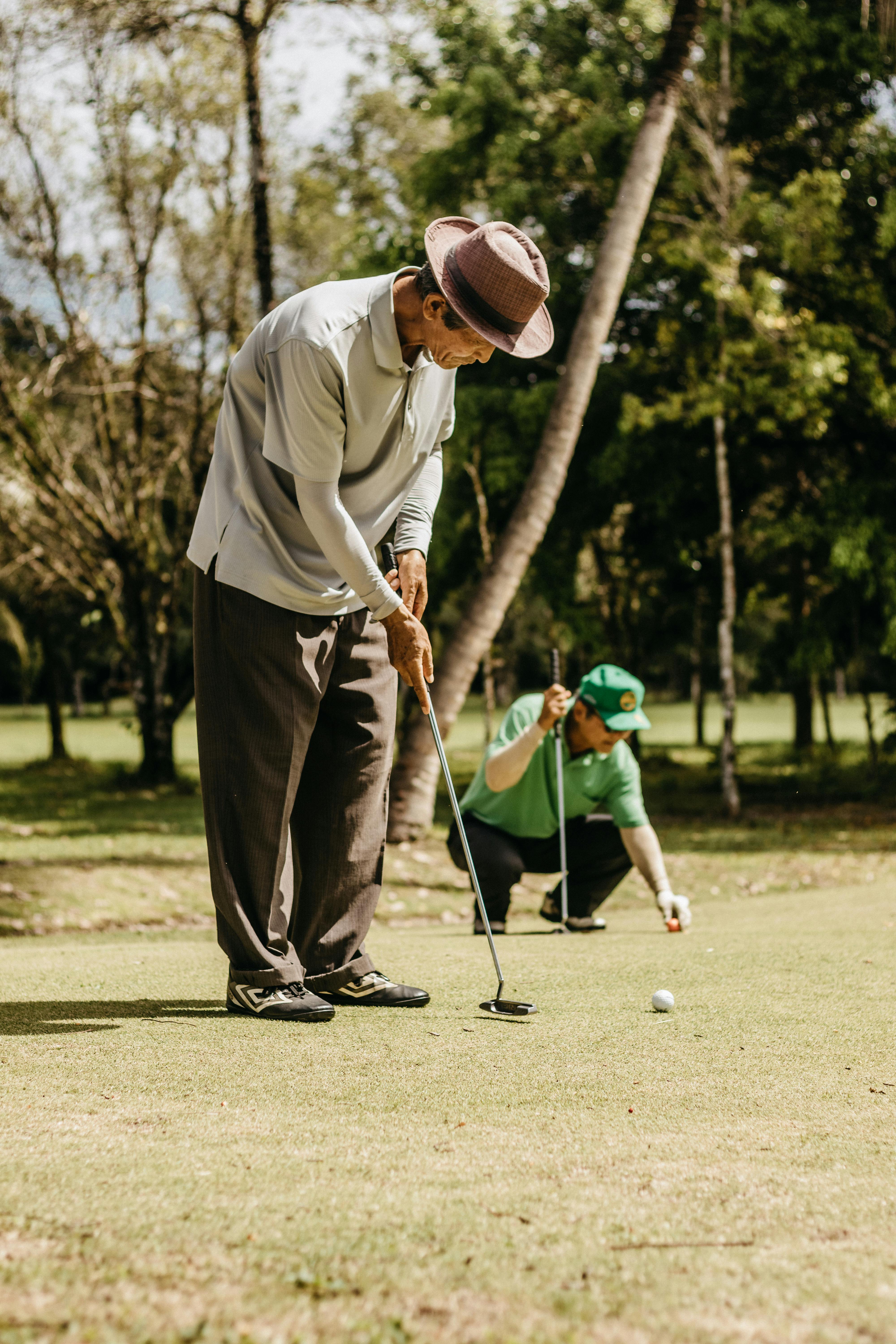 Two senior men playing golf on a sunny day, illustrating focus and sportsmanship.