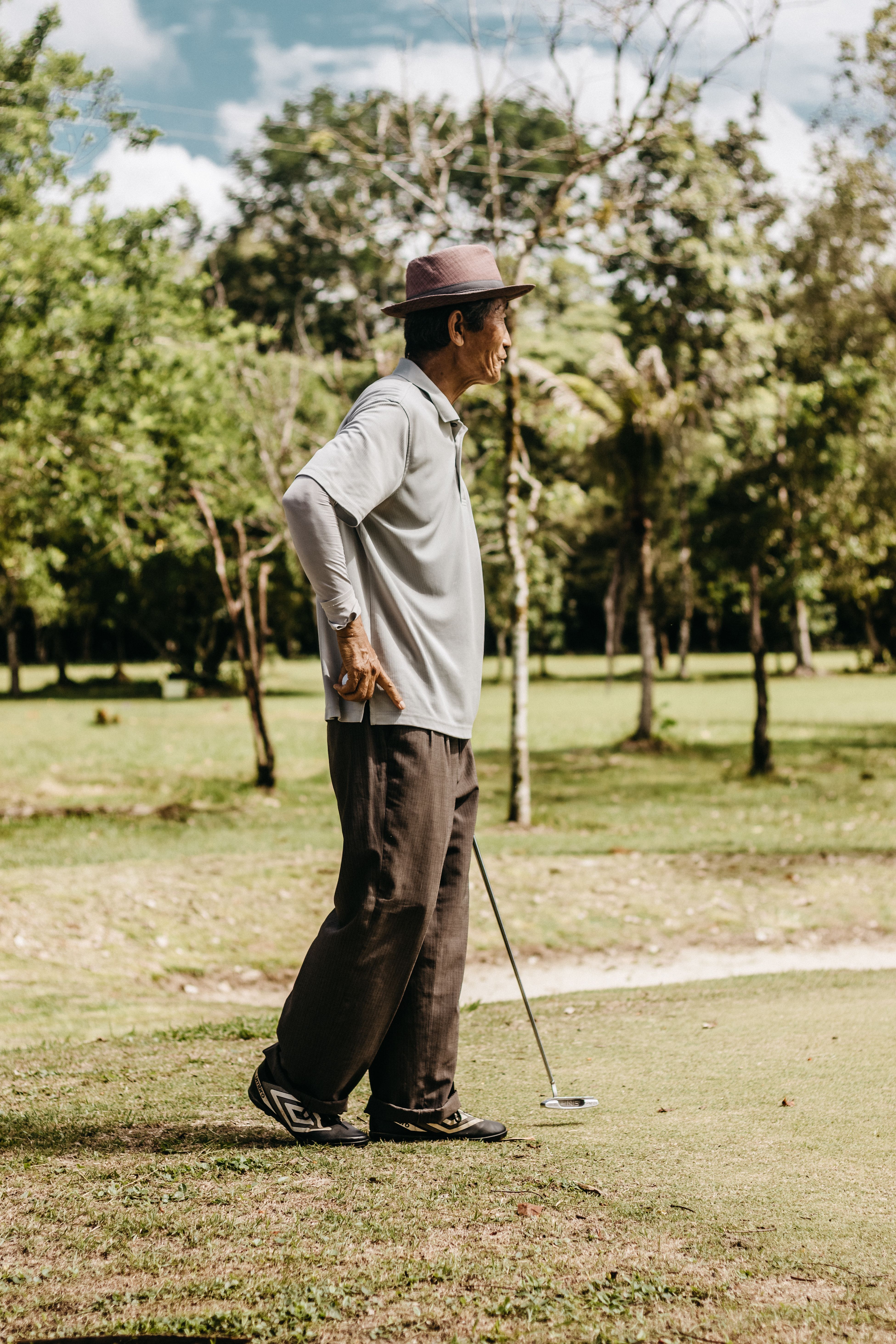 Senior man playing golf on a lush green course, enjoying a sunny day outdoors.