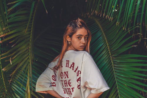 Woman in T-shirt Posing among Leaves