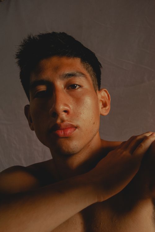 Free Dark, moody portrait of a topless young man with short black hair against a gray background. Stock Photo
