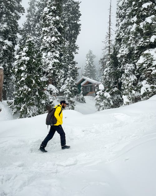 Man in Yellow Jacket Walking on Snow Covered Ground