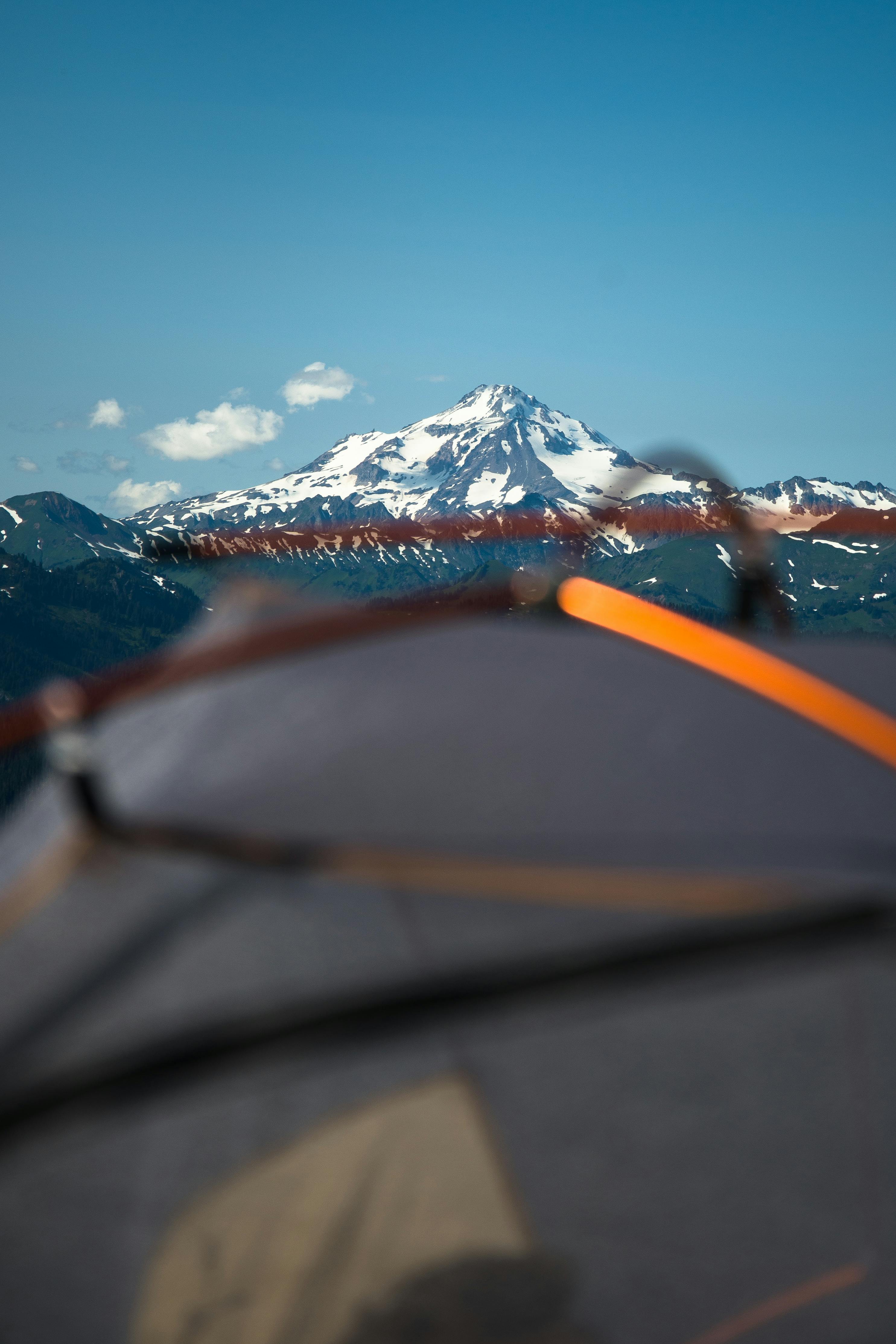 在晴朗的蓝天下搭建的帐篷里，欣赏雪山的壮丽景色