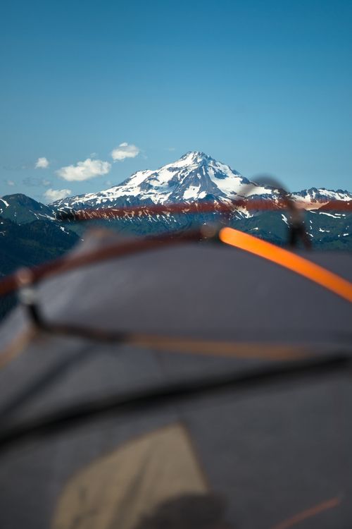 Free A breathtaking view of a snow-capped mountain through a tent setup under a clear blue sky. Stock Photo