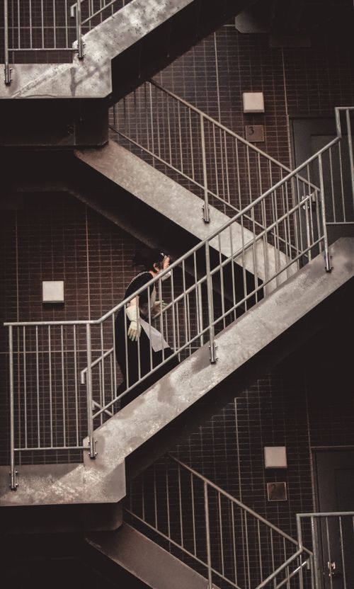 Free A woman climbs an industrial staircase in a modern urban setting. Stock Photo