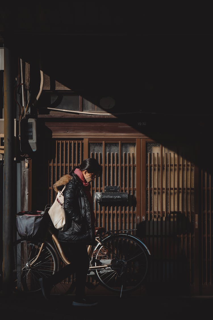 Woman Passing Near Bicycle By Fence