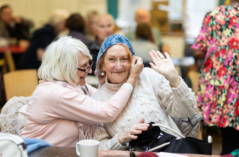 Two older women laughing together over coffee
