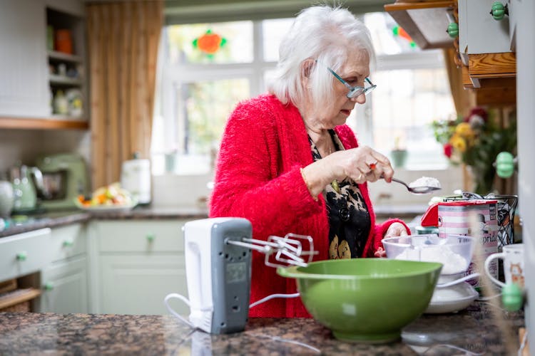 Elderly Woman With Eyeglasses Preparing Dough In Kitchen