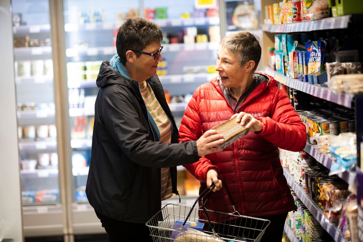 Two shoppers examining a product pack together in a retail aisle