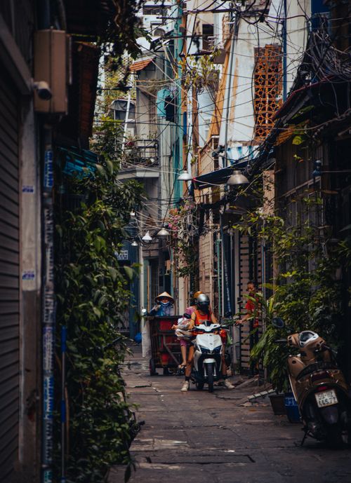 Free Narrow urban alley with vegetation and scooters, capturing local life and architecture. Stock Photo