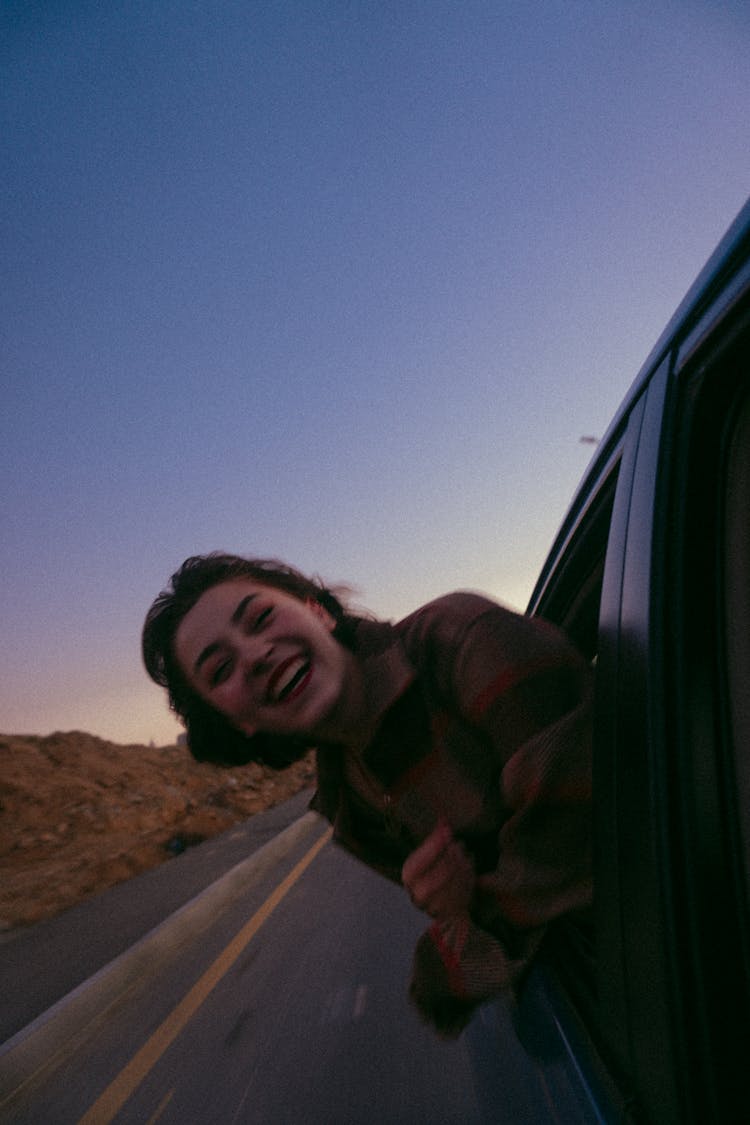 Laughing Girl Sticking Her Head Out Of A Car Window 