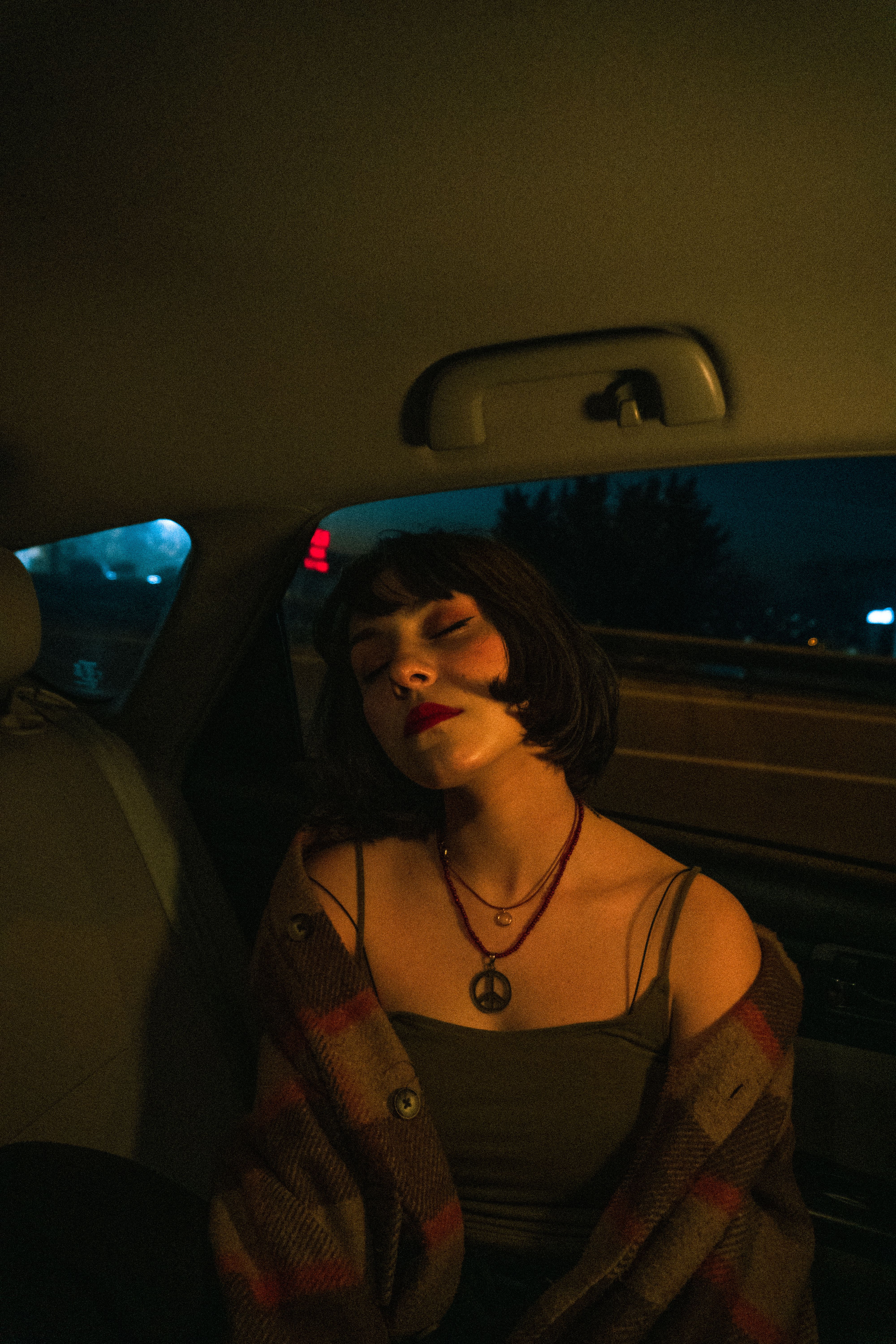 Young woman relaxing in a car at night, capturing a serene travel moment.