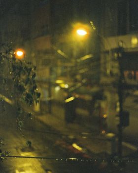 Blurred night street scene in Ho Chi Minh City with rain and streetlights.