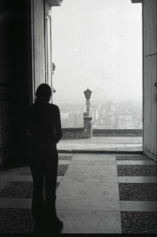 Free Black and white silhouette of a person looking at a misty cityscape through an open doorway, creating a contemplative mood. Stock Photo