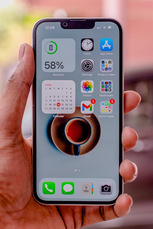 Close-up of a Man Holding an iPhone Displaying the Home Screen 