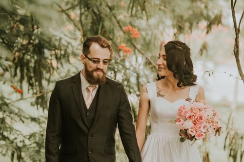 Free A newlywed couple smiles and walks together outdoors in a romantic setting. Stock Photo
