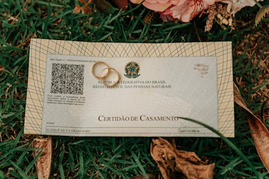 Close-up of a Brazilian marriage certificate with wedding rings and flowers on grass.