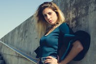 在城市环境中，一位金发碧眼的时尚女性正对着混凝土墙摆姿势