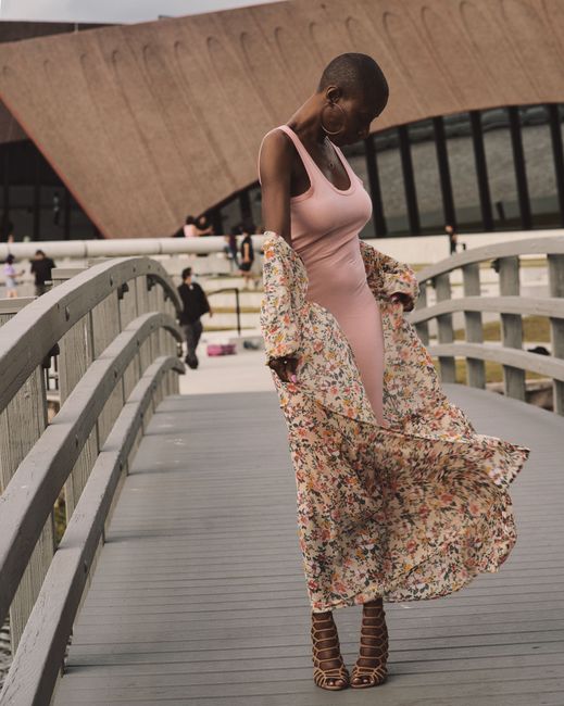 Stylish woman in pink dress on a footbridge, showcasing modern urban fashion. Perfect for lifestyle imagery.