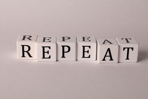 Photo of Cubes with Letters Forming the Word "Repeat"