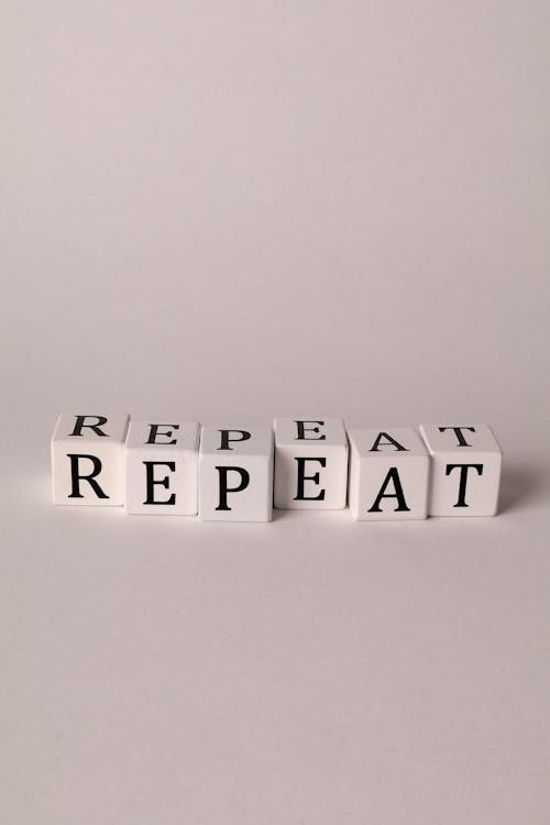 Photo of Cubes with Letters Forming the Word "Repeat"