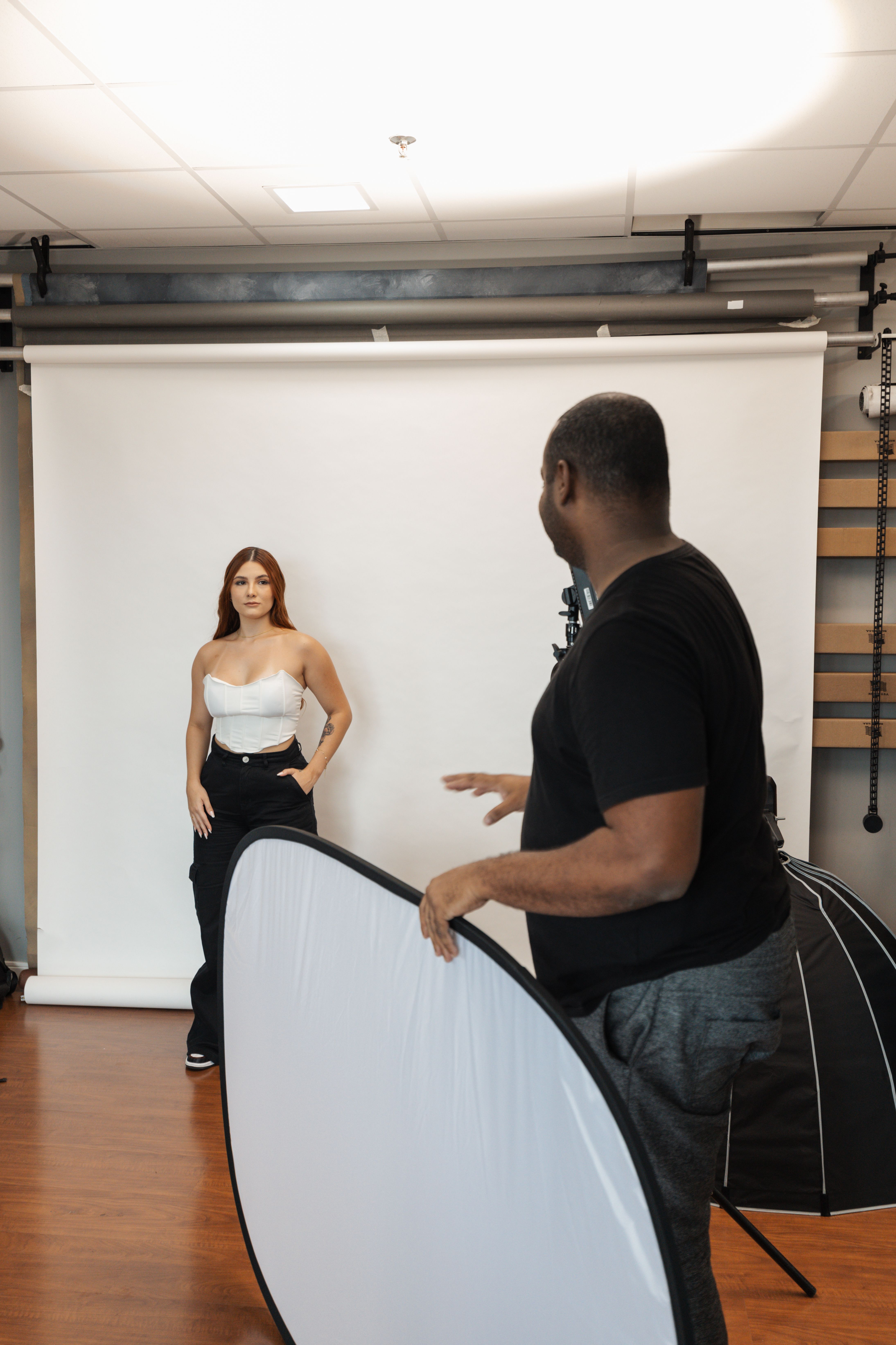 Photographer directs model during a professional fashion photoshoot in a studio.